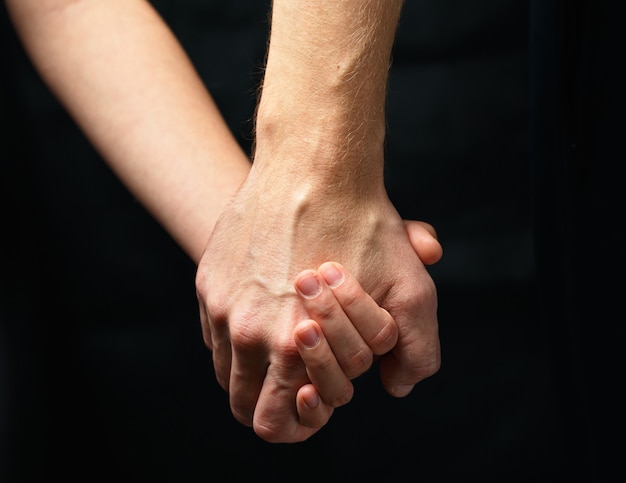 Mâle main tient la main féminine sur fond sombre