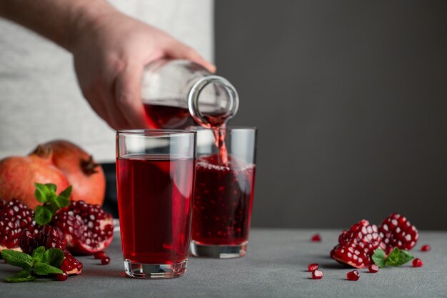 Mâle main verser le jus de grenade d'une bouteille dans un verre