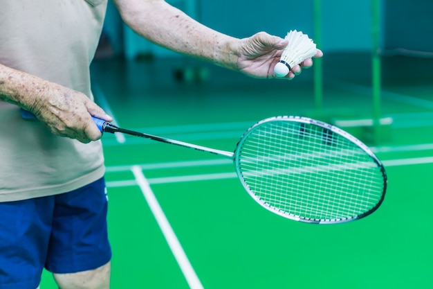 Mâle seul joueur senior badminton main tient coq navette blanche