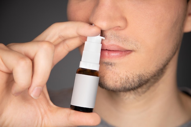 Le mâle utilise un vaporisateur nasal et applique la bouteille sur son nez