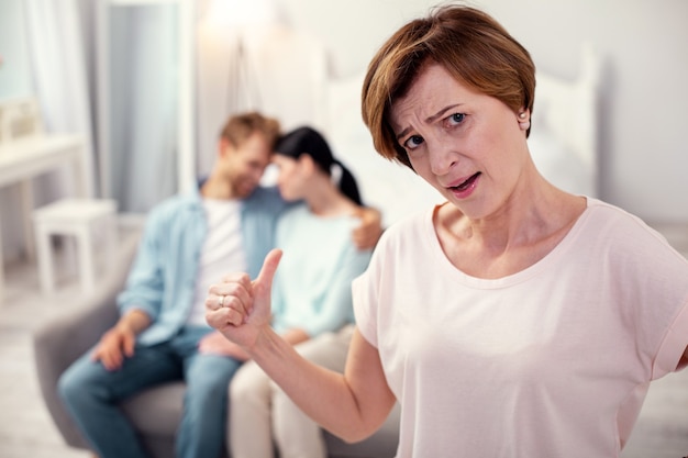 Photo malheureuse belle-mère. femme âgée sans joie vous regarde tout en s'inquiétant pour son fils