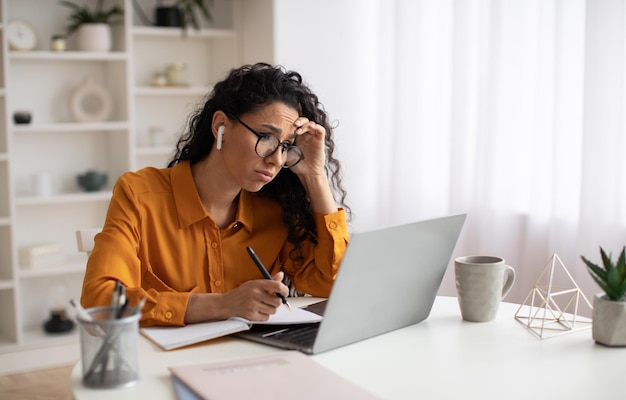 Malheureuse femme d'affaires utilisant un ordinateur portable ayant des problèmes de travail en ligne au bureau