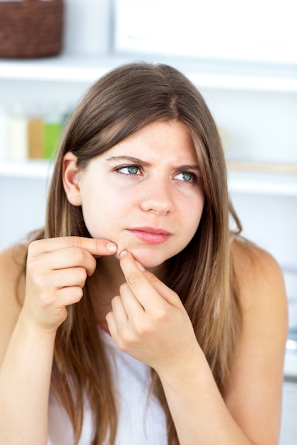 Malheureuse femme avec irritation cutanée en train de nettoyer son visage