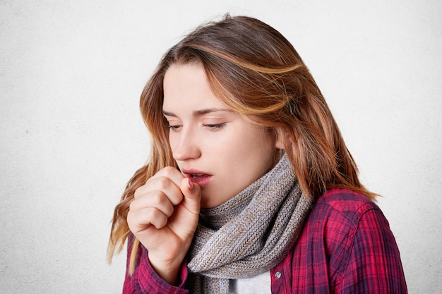 Malheureuse femme qui tousse prise au froid par temps glacial, porte une écharpe chaude sur le cou