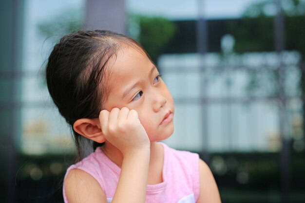 Malheureuse petite fille enfant avec posture sa main sur la joue.