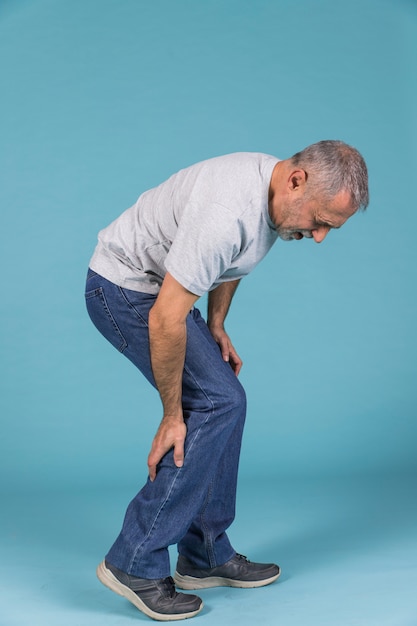 Malheureux homme souffrant de douleurs aiguës sur fond bleu