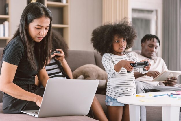 Maman d'affaires travaillant femme mère occupée vacances travail sans fil sur ordinateur portable à la maison avec sa fille et sa famille