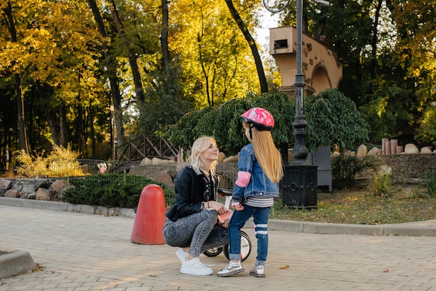 Maman aide à habiller l'équipement et le casque de sa petite fille pour une balade en Segway dans le parc