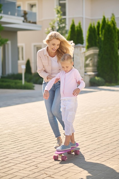 Maman aide sa fille à faire du skateboard