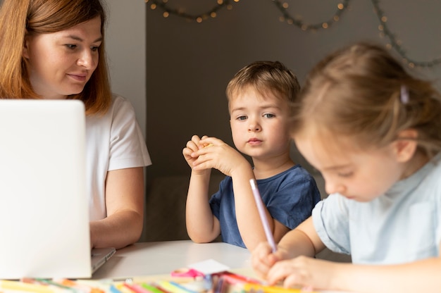 Photo maman aide ses enfants à faire leurs devoirs