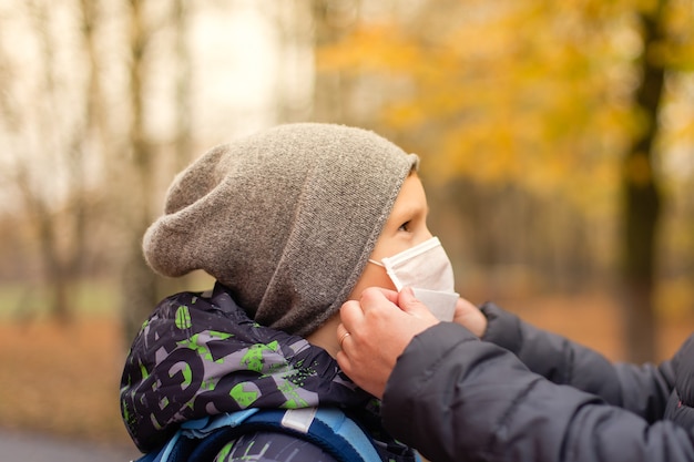 La maman ajuste le masque à l'enfant dans la rue