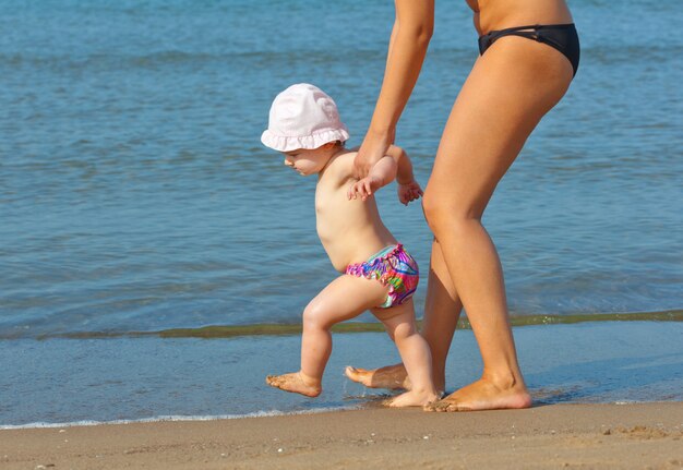 Maman apprend à sa fille à marcher jusqu&#39;à la plage.