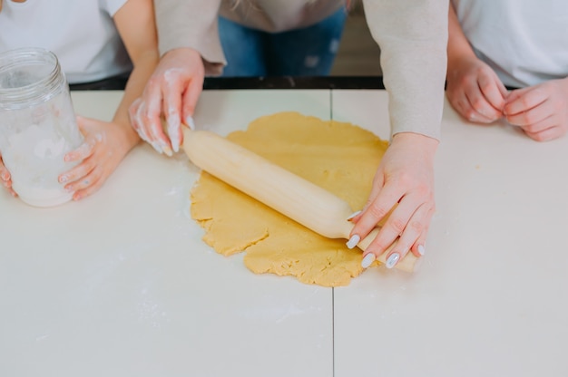 Maman apprend à ses filles à faire cuire de la pâte dans la cuisine.