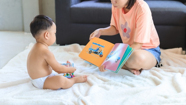 Maman asiatique lisant un livre avec son fils