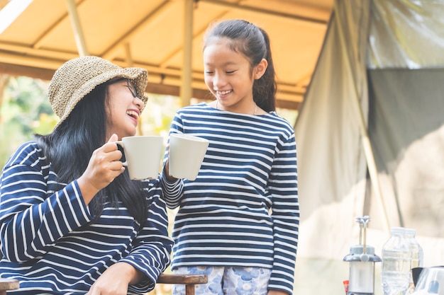 Maman asiatique et sa fille aiment boire un verre au camping