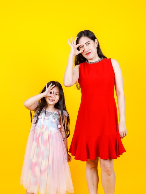 Maman asiatique et sa fille prenant une photo de portrait ensemble sur fond jaune avec drôle et charmant.