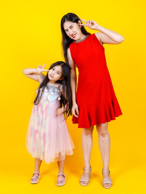 Maman asiatique et sa fille prenant une photo de portrait ensemble sur fond jaune avec drôle et charmant.