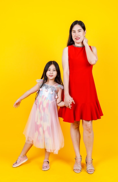 Maman asiatique et sa fille prenant une photo de portrait ensemble sur fond jaune avec drôle et charmant.