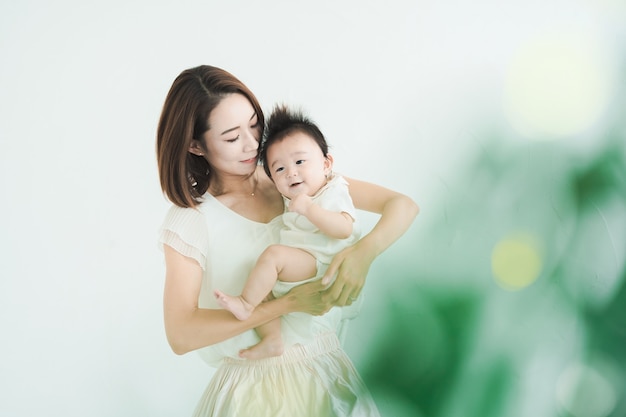 Maman asiatique tenant un bébé dans la pièce lumineuse