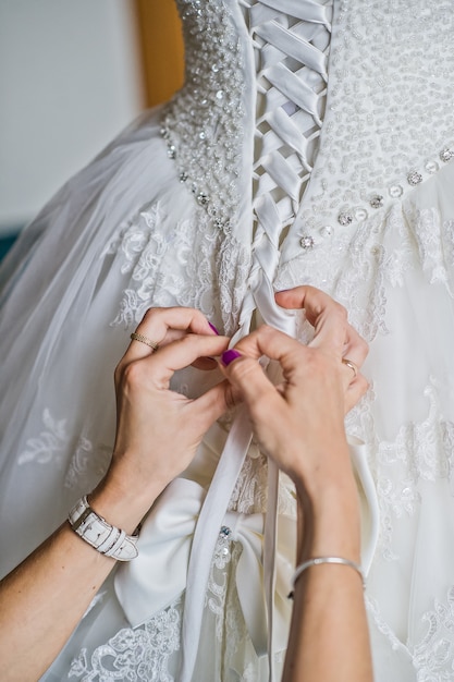 Maman attachant la robe de mariée de la mariée, l&#39;intérieur de l&#39;hôtel