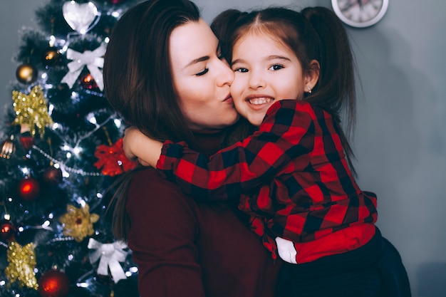 Maman baise une petite fille à l'arbre de Noël