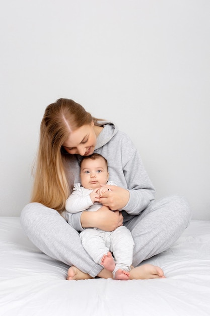 Maman et bébé jouent sur le lit Mère et fils famille heureuse belle fille blonde et bébé mignon à la maison