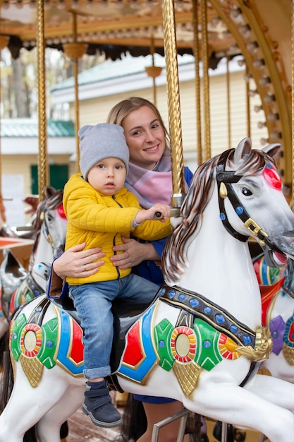 Maman avec un bébé joyeux sur un carrouselPetit fils avec maman dans le parc