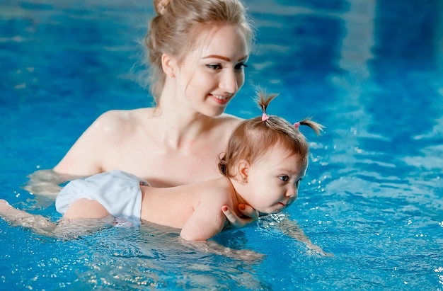 Maman et bébé nagent dans la piscine.