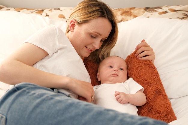 Maman avec un bébé nouveau-né se trouve sur le lit, la mère embrasse l'amour de la mère de l'enfant