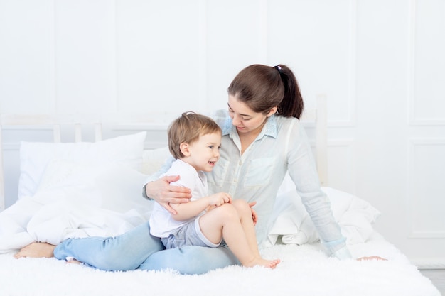 Maman et bébé parlent à la maison sur le lit, le concept de la relation entre parents et enfants.