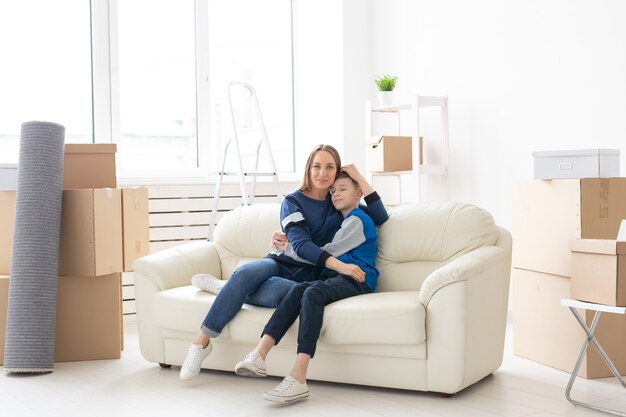 Maman célibataire mignonne et petit garçon se relaxant après le déménagement. Le concept d'hypothèque de pendaison de crémaillère et la joie d'un nouveau logement.