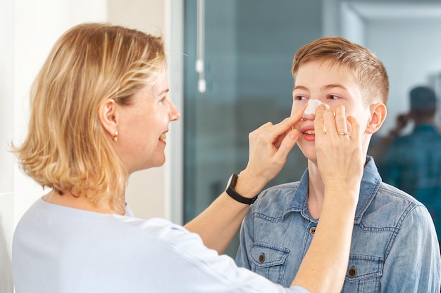 maman colle un patch pour enlever les points noirs à son fils patch anti-acné adolescent avec pansement nasal