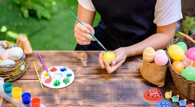 Maman colorie les oeufs pour la fête de Pâques en avril. Préparation et peinture pour la fête de famille et la décoration de la maison.