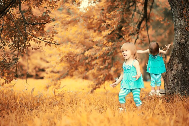 Maman avec deux filles jumelles pour une promenade dans le parc en automne