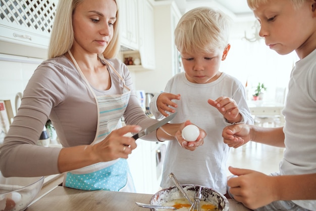 Maman avec deux fils cuisine tarte de vacances dans la cuisine. Vie occasionnelle