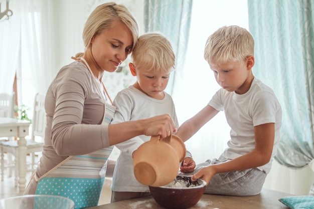 Maman avec deux fils cuisine tarte de vacances dans la cuisine. Vie occasionnelle