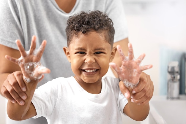 Maman a dit que les germes sont mauvais Photo d'un adorable petit garçon debout dans la salle de bain et se lavant les mains pendant que sa mère l'aide