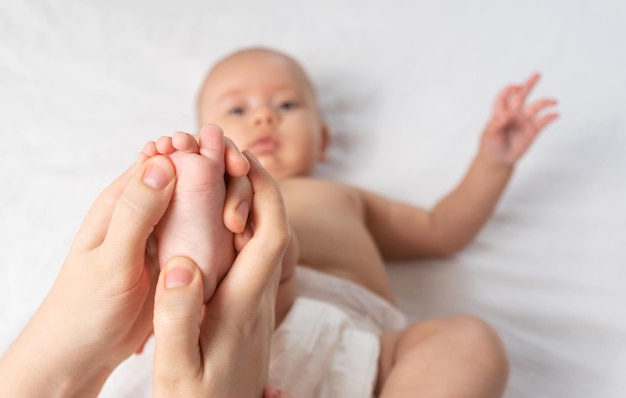 Maman donne un massage des pieds à bébé. Mise au point sélective