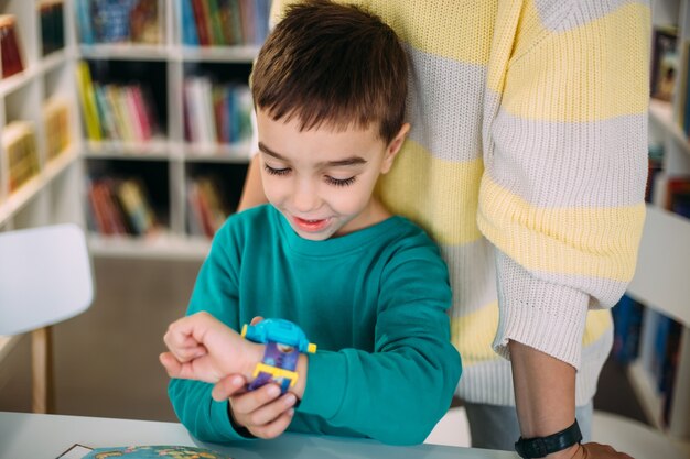 Maman donne à son fils sa première montre en apprenant à déterminer l'heure par l'horloge