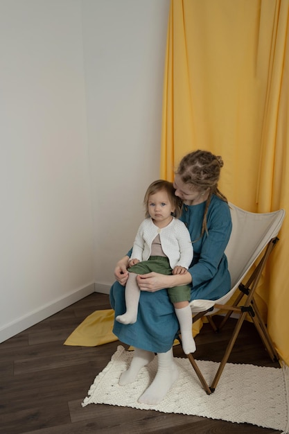 Maman avec des dreadlocks s'occupe de l'enfant assis sur une chaise