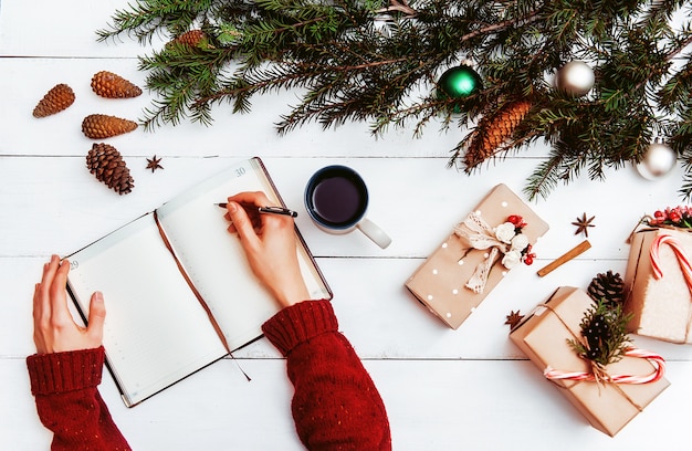 Maman écrit dans un cahier et une liste de cadeaux pour Noël et le Nouvel An