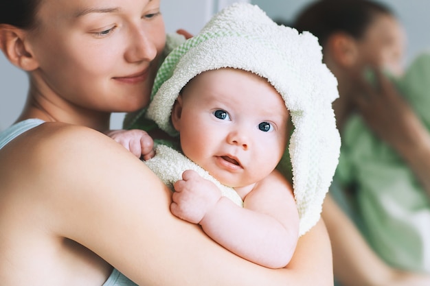 Maman embrasse son petit bébé le plus mignon après le bain avec une serviette sur la tête