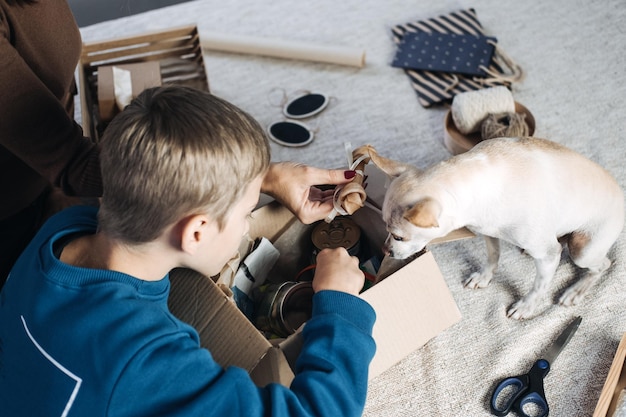 Maman et enfant de famille heureux mettant l'os dans la boîte d'abonnement d'animal familier pour les chiens chien chihuahua et