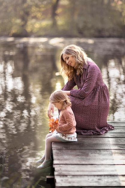 Maman avec enfant fille dans le parc au coucher du soleil soirée ensoleillée enfance heureuse lac Countyside