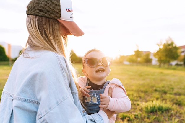 Maman l'enfant joue dans le parc l'enfant porte les lunettes de soleil de maman