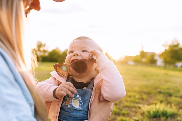 Maman l'enfant joue dans le parc l'enfant porte les lunettes de soleil de maman