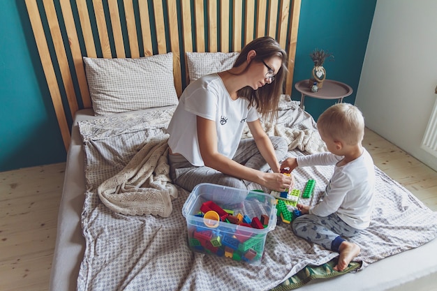 Maman et enfant jouent ensemble dans la chambre avec des blocs en plastique