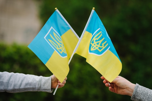 Maman et enfant tenant un drapeau dans leurs mains lors d'un rassemblement Le drapeau jaune et bleu ukrainien flotte dans le vent à l'extérieur Symbole national de la liberté et de l'indépendance patriotisme Aucune guerre n'arrête l'agression russe