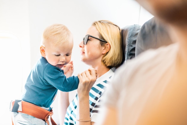 Maman et enfant volant en avion mère tenant et jouant avec son bébé bébé garçon enfant sur ses genoux