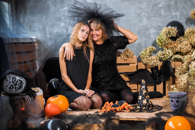 Maman avec enfants fille fille 12 ans parmi décor aux tons orange et noir pour halloween s'amuser et passer du temps ensemble